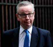 Michael Gove looks confused in a suit and tie standing outside Downing Street