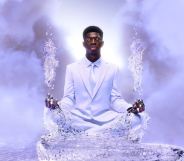 Lil Nas X sits in a white suit on a pathway made of ice floating in the skies