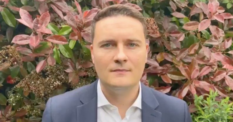 Wes Streeting wearing a shirt and blazer in front of a bush