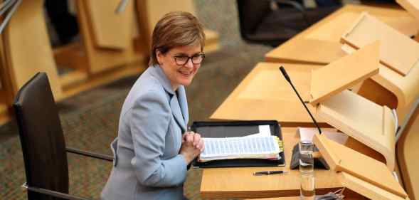 Nicola Sturgeon sits down in Holyrood in a blue pant suit