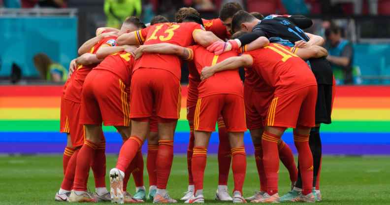 Denmark players form a circle in front of a rainbow advert during the UEFA Euro 2020 Championship Round of 16 match between Wales and Denmark