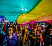 People hold up an LGBT+ Pride flag during a march