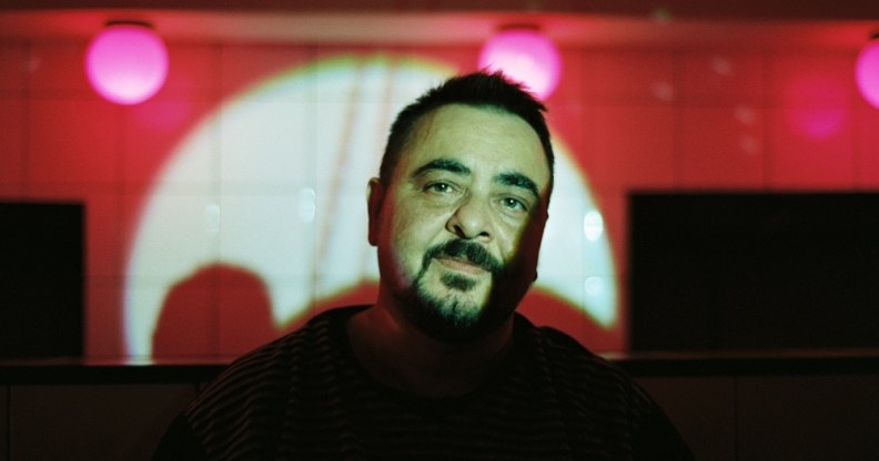 Bart Nikolo stands in front of a bar theatre stage with a spotlight shining on him