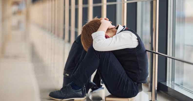 Boy in uniform sitting alone with feeling sad at school. Conception of harassment.