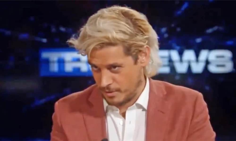 Milo Yiannopoulos looks down while wearing a shirt and blazer