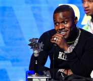 DaBaby speaks in a black sweatshirt onstage at the BET Hip Hop Awards 2019