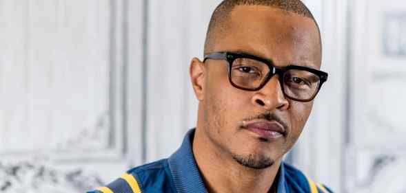 T.I. looks to the camera in a blue bomber jacket and black glasses