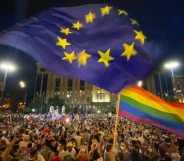 Thousands in front of the Georgian Parliament Building waving LGBT+ Pride flags