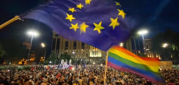 Thousands in front of the Georgian Parliament Building waving LGBT+ Pride flags