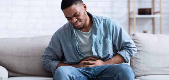 A Black man having a painful stomach ache, caressing his tummy