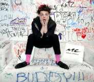 Yungblud, real name Dominic Harrison, visits Music Choice in 2019 and poses against a background of graffiti while sitting on a sofa