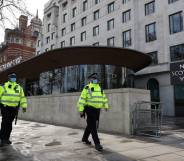 Police officers wearing face coverings due to Covid-19 walk past New Scotland Yard, the headquarters of the Metropolitan Police Service