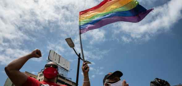 A person flies an LGBT+ Pride flag in Venezuela