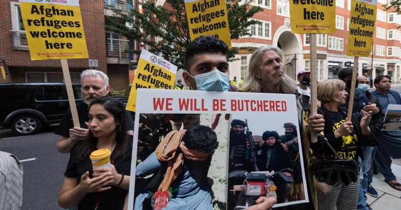 Protestors holding signs reading 'Afghan refugees welcome here' and 'We will be butchered'