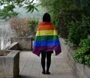 Student with LGBT+ flag draped over their shoulders, photographer from behind, in Beijing, China