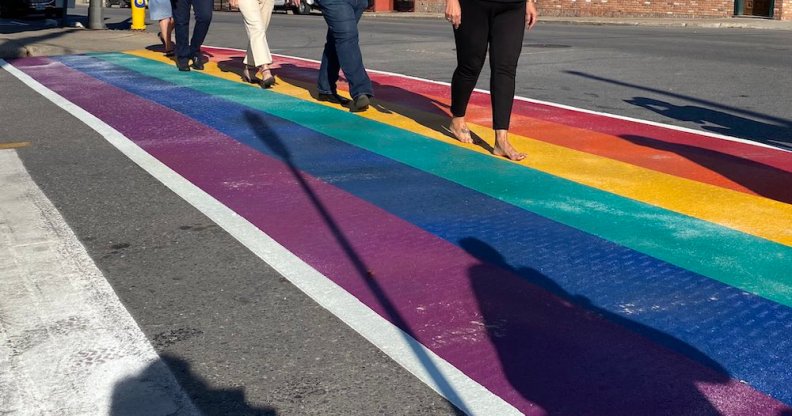 People walk across a rainbow road crossing in Port Colborne, Canada