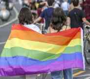 Two women hold the rainbow pride flag as they take part in the Queerschutz Now march in Berlin, Germany