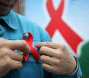 A photo of a person putting on a red ribbon for HIV AIDS awareness on World AIDS Day