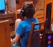 A 12-year-old sits on a wooden chair playing video games