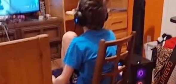 A 12-year-old sits on a wooden chair playing video games