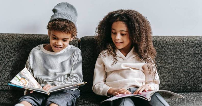 Two children are sitting on a couch and reading books