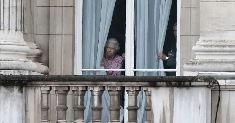 The Queen looking out of her window at Buckingham Palace.