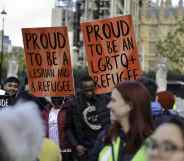 Protesters buttress placards up high standing in solidarity with queer refugees in Parliament Square