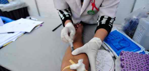 A medical official takes blood from a person for rapid HIV testing