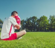 Man sitting on a football pitch crying