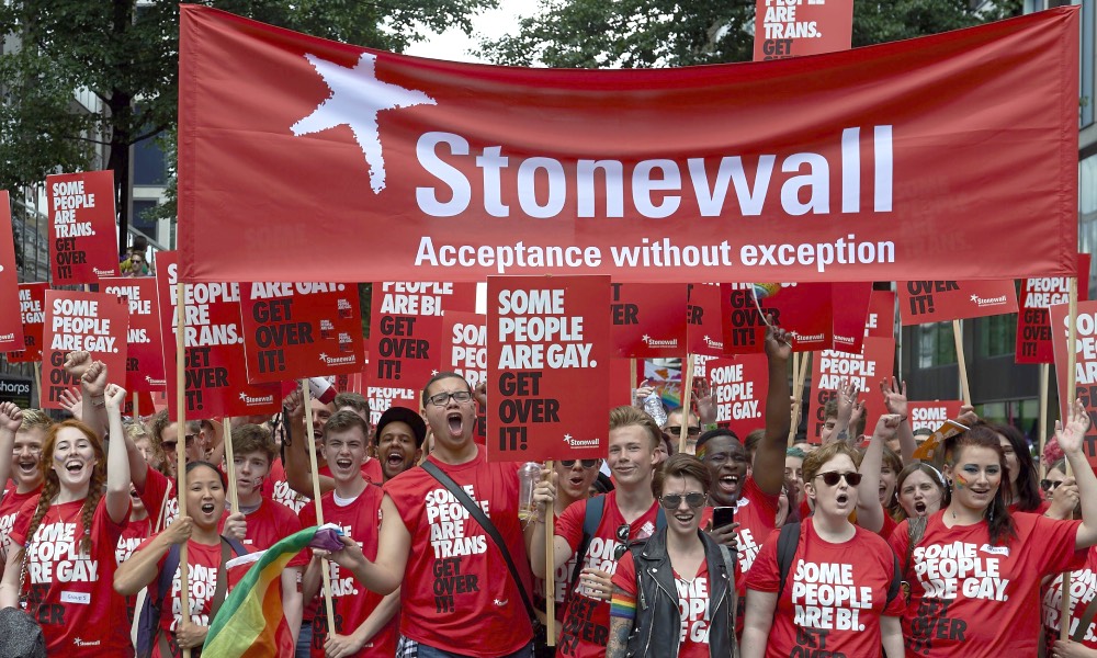 Protesters holding placards saying 'some poeple are gay/bi/trans, get over it'