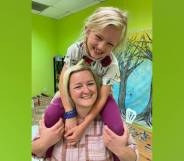 Sunny Bryant smiles and sits on the shoulders of her mum, Bekah