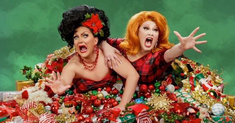 Jinkx Monsoon and BenDeLaCreme bursting out of a pile of presents.