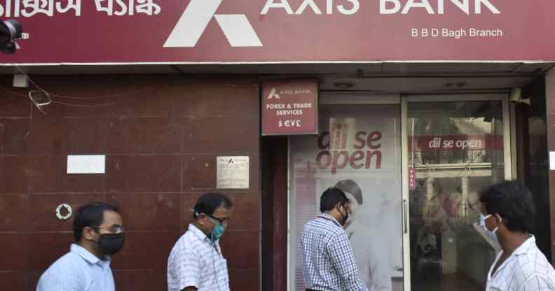 People walk past an Axis Bank in Kolkata, India