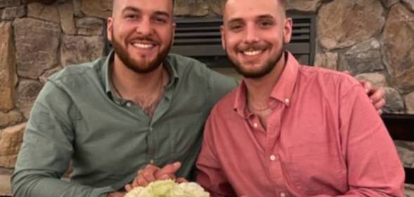 Husbands Reid Alexander and Rafael Díaz pose for a photo and hold hands