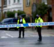 Police officers stand behind a cordon