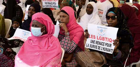 A woman in Senegal holds a sign reading 'LGBT is a threat for humanity' during a protest called by religious associations against homosexuality in 2021