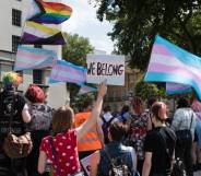 People hold up trans pride flag, non-binary flag and progressive pride flags in a protest outside Downing Street