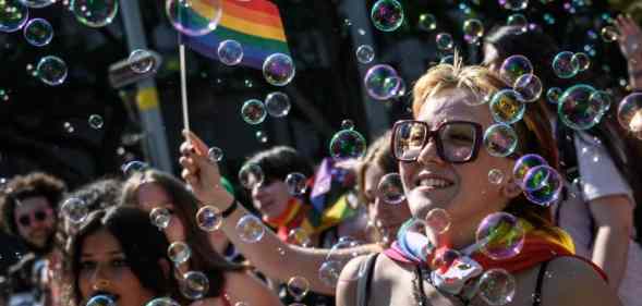 Members of the LGBT+ community in Switzerland celebrate Zurich Pride holding rainbow LGBT+ flags and walking through a wave of bubbles