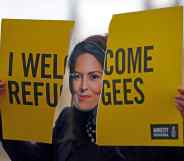 An activist from Amnesty International wears a mask depicting Britain's Home Secretary Priti Patel