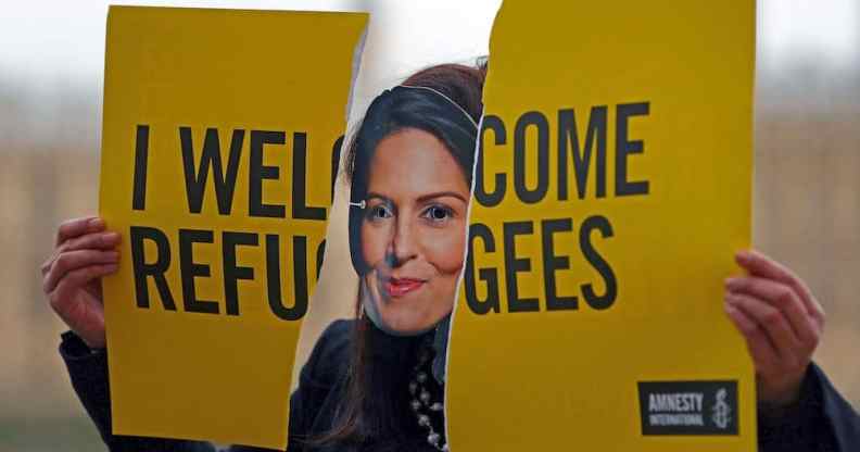 An activist from Amnesty International wears a mask depicting Britain's Home Secretary Priti Patel