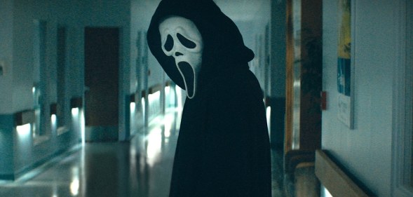 Ghostface in Scream standing in a corridor