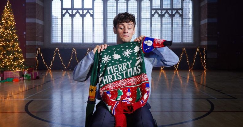 Tom Daley holding up a Merry Christmas jumper