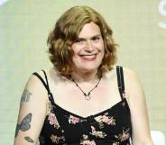 Lilly Wachowski wears a black patterned dress and sits in front of a grey-green background