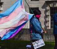 A protester holds a trans pride flag and a placard that reads "Protect Trans Kids" placard during the trans rights demonstration