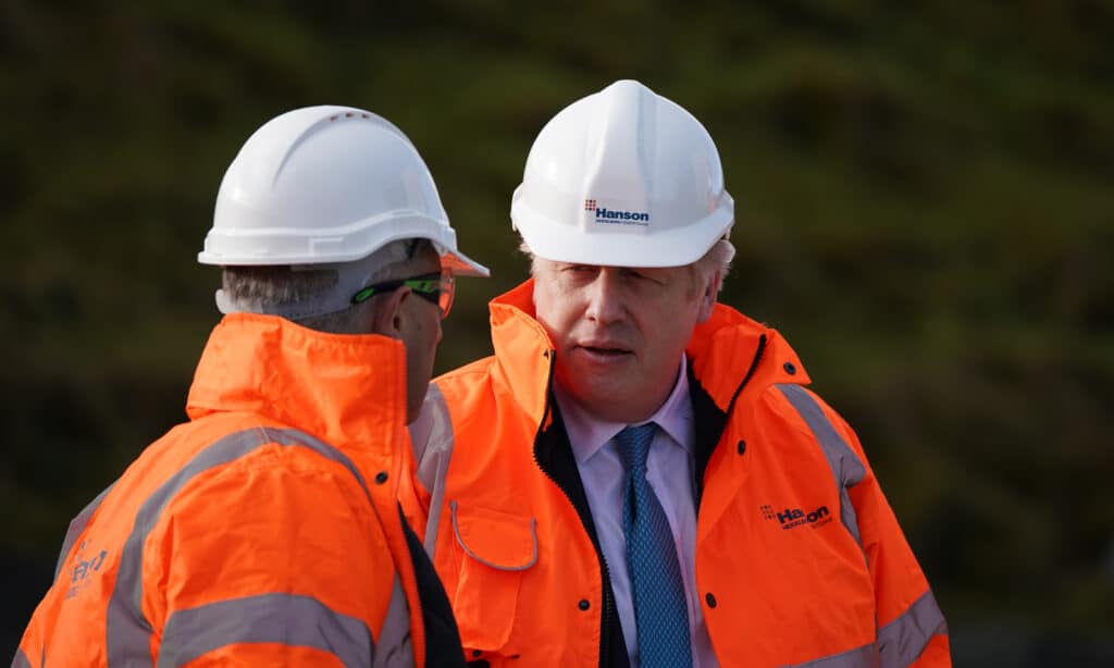 Boris Johnson wearing a hard hat and orange hi-res jacket over his suit