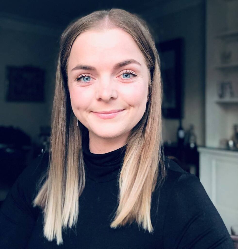 Laura Jamieson wears a black turtleneck top and smiles at the camera