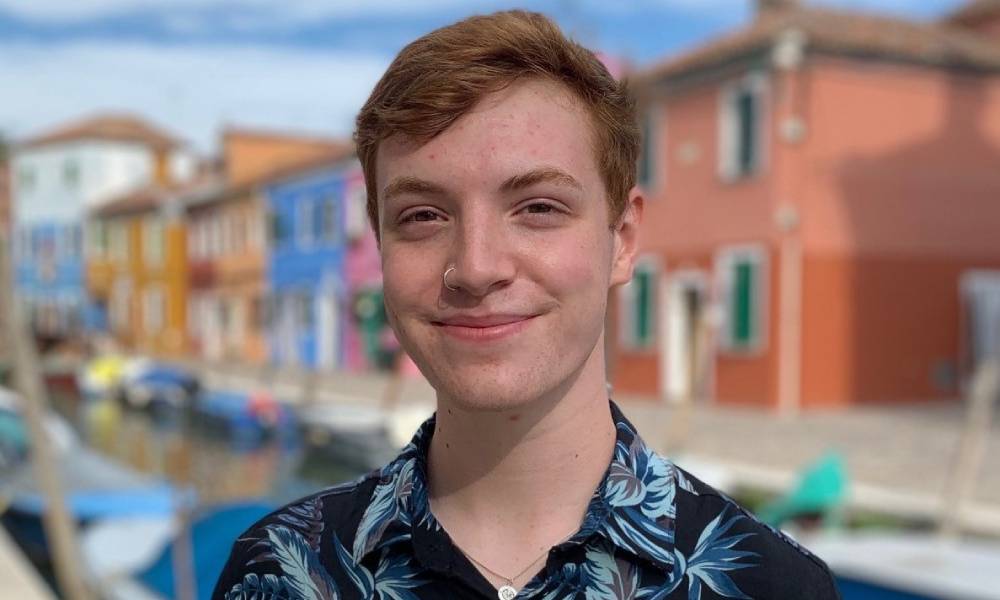 Rian Leggett smiles at the camera while wearing a blue floral print shirt