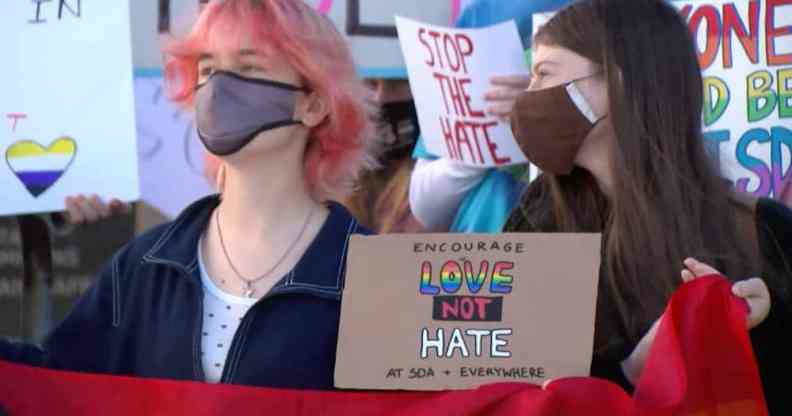 People hold a sign that reads 'Encourage love not hate at SDA + everywhere'