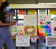 Several LGBT+ posters celebrating Pride month are posted on a glass partition in a high school