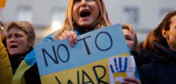 A person holds a sign that reads "No to war" that is in the colours of Ukraine's flag to protest Russia's invasion of the country